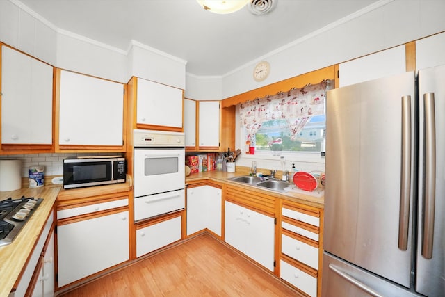 kitchen with sink, appliances with stainless steel finishes, white cabinetry, and tasteful backsplash