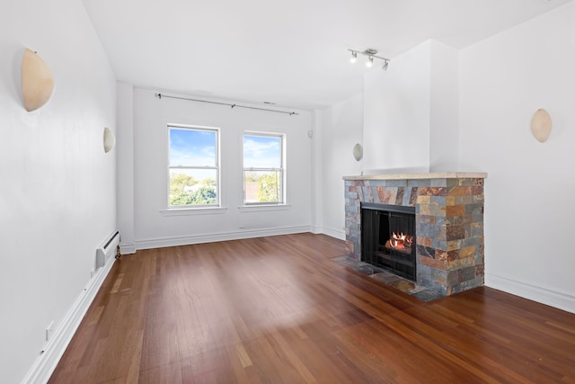 unfurnished living room featuring wood-type flooring, a baseboard heating unit, and a fireplace