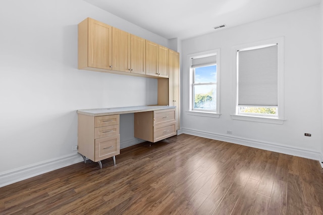 unfurnished office featuring built in desk and dark hardwood / wood-style flooring