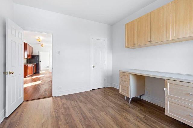 unfurnished office featuring dark hardwood / wood-style floors and built in desk