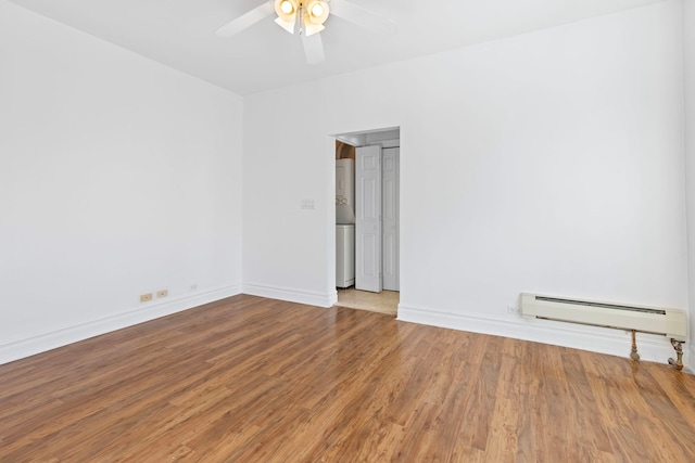 spare room featuring baseboard heating, hardwood / wood-style floors, and ceiling fan