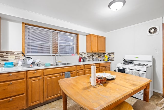 kitchen featuring backsplash, sink, white range with gas cooktop, crown molding, and light tile patterned floors