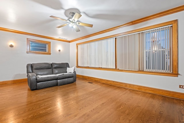 living room with crown molding, wood-type flooring, and ceiling fan