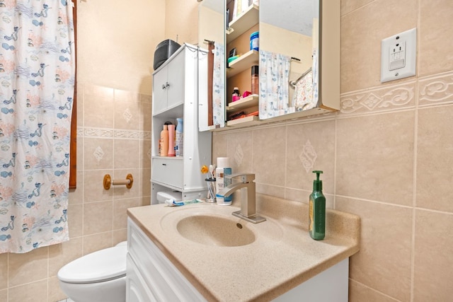 bathroom with vanity, toilet, and tile walls