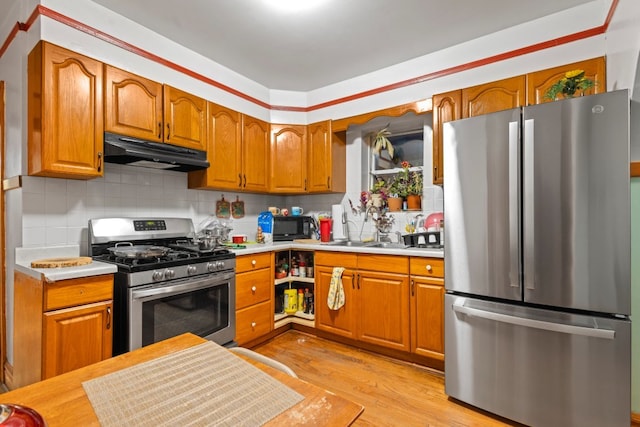 kitchen featuring backsplash, stainless steel appliances, and light wood-type flooring