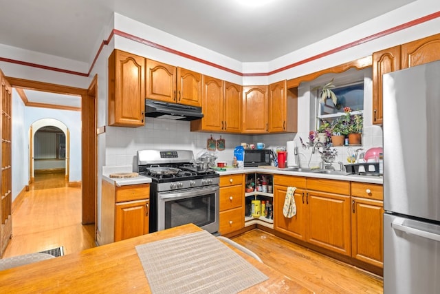 kitchen with backsplash, stainless steel appliances, and light wood-type flooring