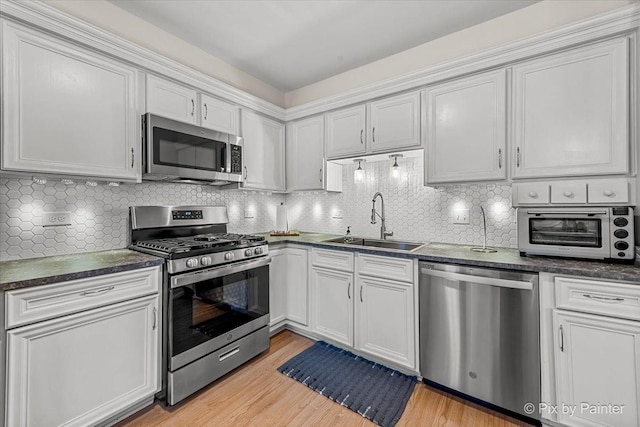 kitchen featuring decorative backsplash, white cabinetry, sink, and appliances with stainless steel finishes