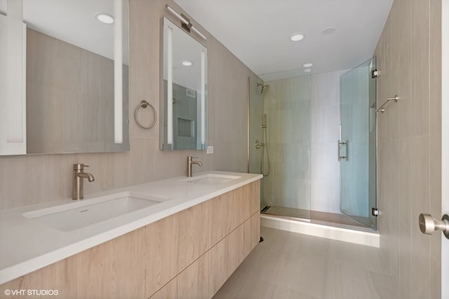 bathroom with vanity, a shower with shower door, tile patterned floors, and tile walls