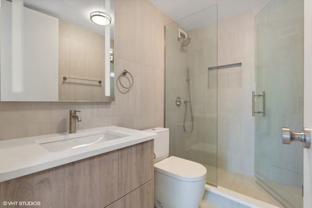 bathroom with a shower with door, tasteful backsplash, toilet, tile walls, and vanity