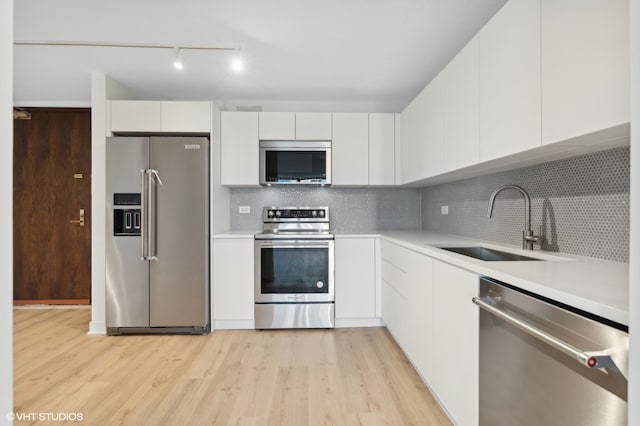 kitchen with light hardwood / wood-style floors, white cabinetry, stainless steel appliances, and sink