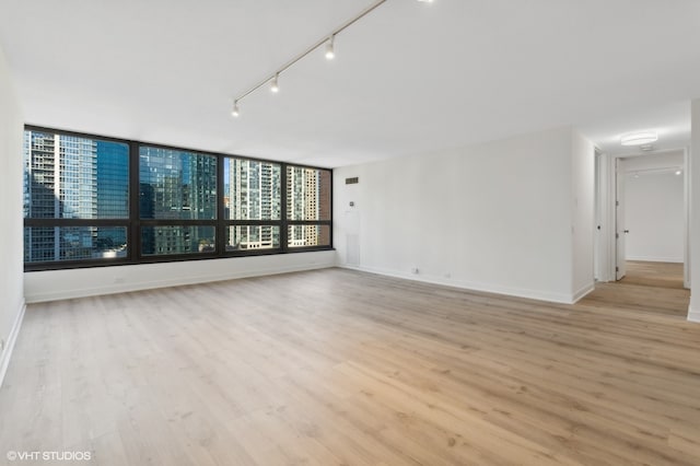 empty room featuring rail lighting and light hardwood / wood-style floors