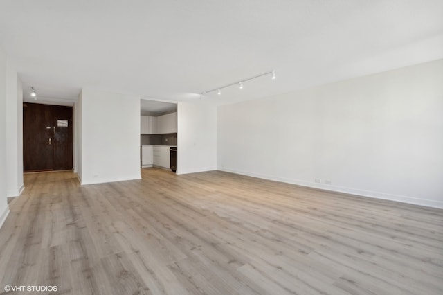 empty room with track lighting and light wood-type flooring