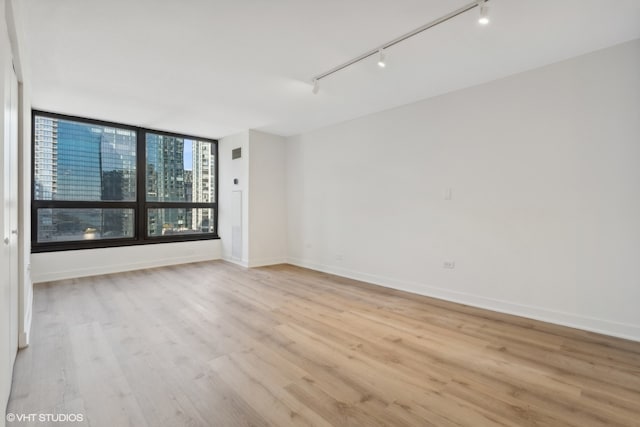 unfurnished room featuring track lighting and light hardwood / wood-style flooring