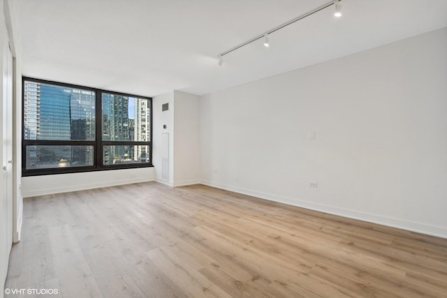 360 E Randolph St Unit 1807, Chicago, IL 60601 - unfurnished room featuring rail lighting, light wood-style flooring, and baseboards