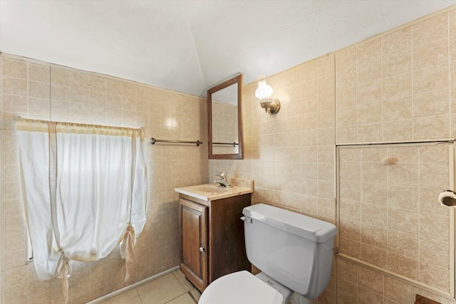 bathroom with lofted ceiling, tile walls, toilet, vanity, and tile patterned floors