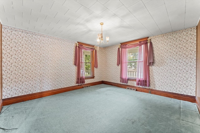 empty room with an inviting chandelier and carpet flooring