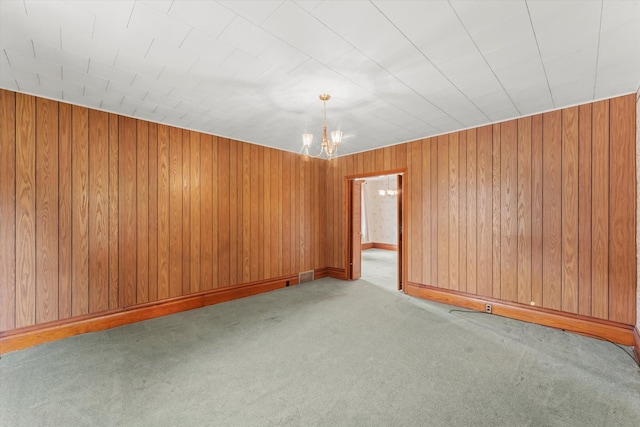 unfurnished room featuring light carpet, a notable chandelier, and wood walls