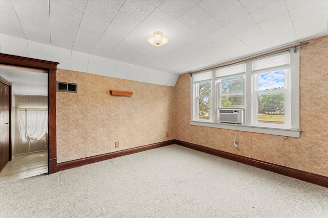 carpeted spare room featuring cooling unit and lofted ceiling