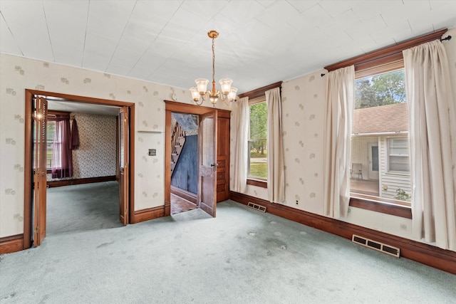 carpeted spare room featuring an inviting chandelier