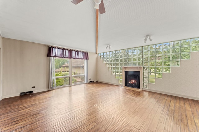 unfurnished living room with hardwood / wood-style floors, a towering ceiling, and ceiling fan