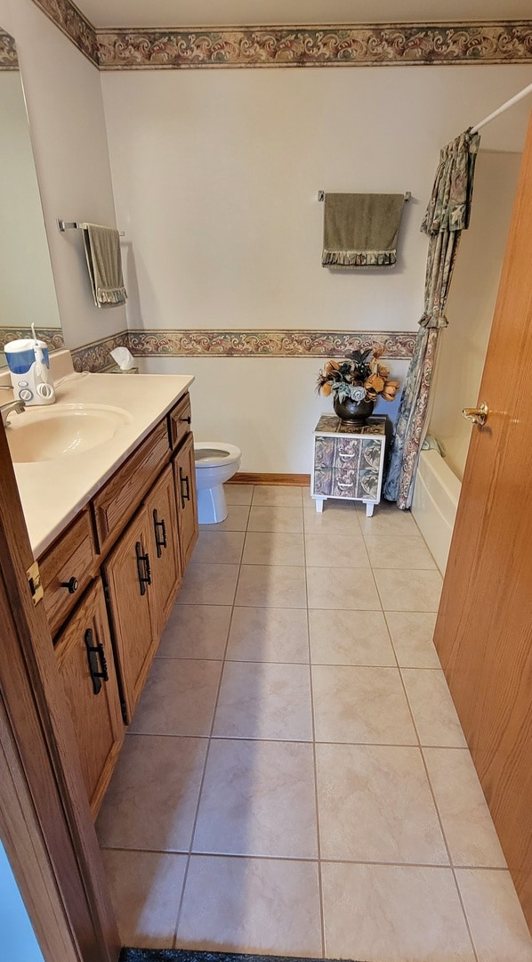 full bathroom with vanity, shower / bath combo with shower curtain, toilet, and tile patterned floors