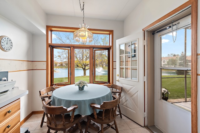 tiled dining space with a water view, an inviting chandelier, and plenty of natural light