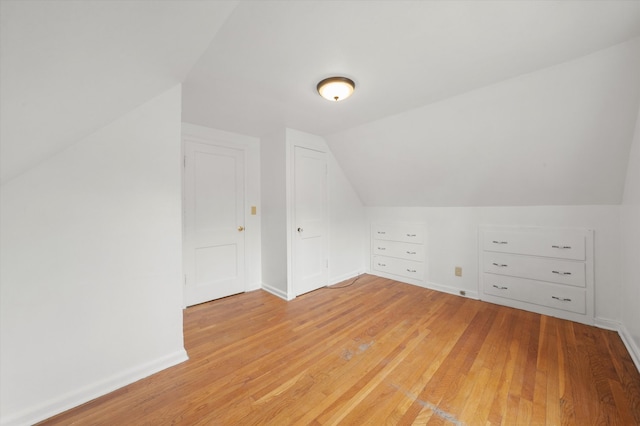 additional living space featuring vaulted ceiling and light hardwood / wood-style floors