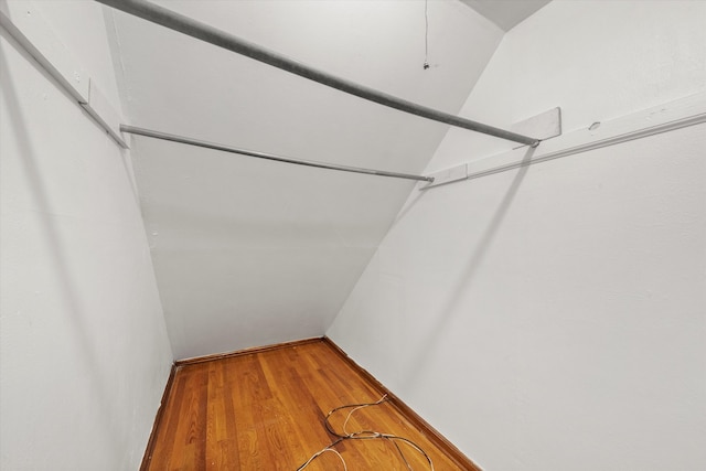 spacious closet with hardwood / wood-style floors and vaulted ceiling