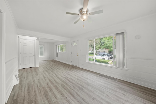 unfurnished living room featuring ceiling fan, ornamental molding, and light wood-type flooring