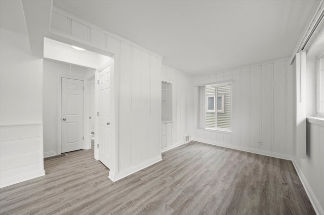 spare room with ornamental molding and light hardwood / wood-style floors