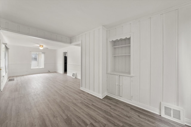 empty room featuring ceiling fan, hardwood / wood-style flooring, and built in features