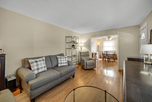 living room featuring a textured ceiling, wood-type flooring, and ceiling fan