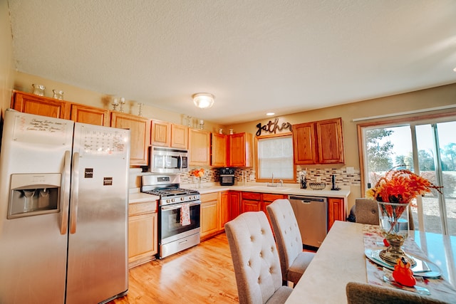 kitchen featuring sink, appliances with stainless steel finishes, decorative backsplash, and light hardwood / wood-style floors