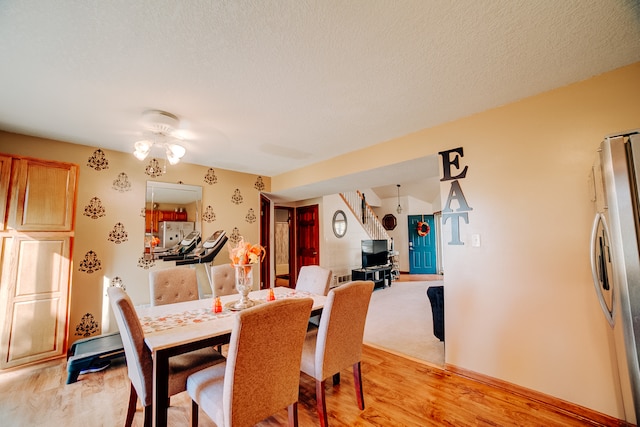 dining space with a textured ceiling, light wood-type flooring, and ceiling fan