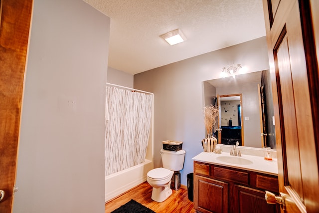 full bathroom with wood-type flooring, a textured ceiling, toilet, vanity, and shower / tub combo with curtain