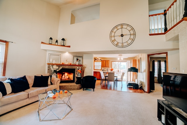 living room with ceiling fan, light carpet, and a towering ceiling