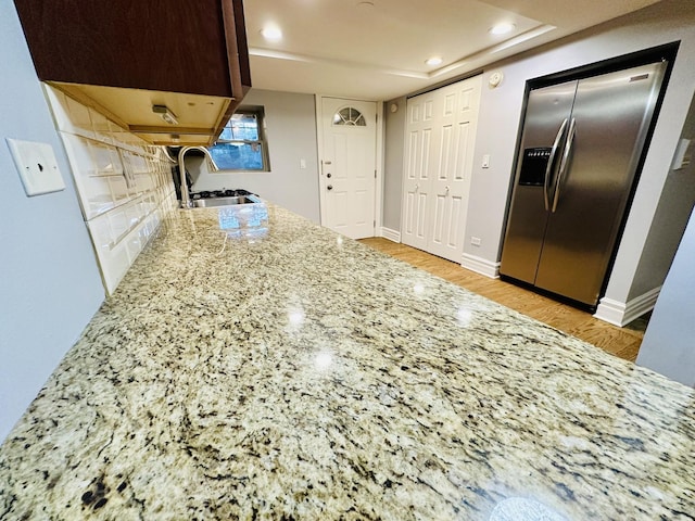 kitchen with light wood-style flooring, a sink, light stone countertops, recessed lighting, and stainless steel refrigerator with ice dispenser