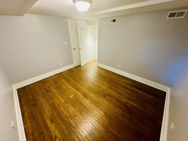 empty room with visible vents, wood finished floors, and baseboards