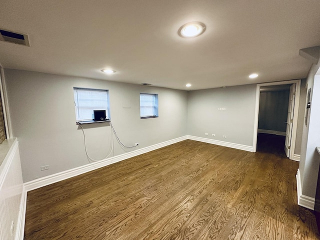 below grade area featuring baseboards, visible vents, dark wood-type flooring, and recessed lighting