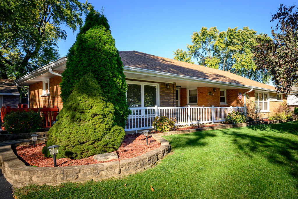 single story home featuring covered porch and a front yard