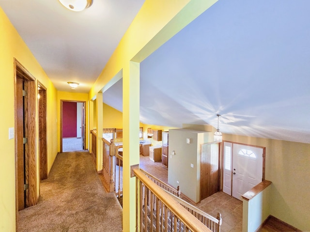 corridor with lofted ceiling and light colored carpet