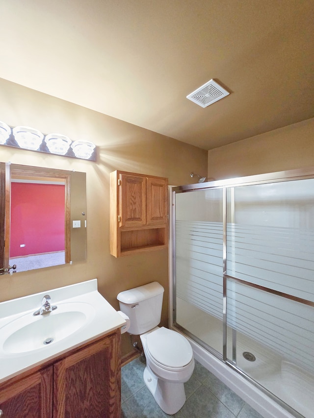 bathroom with vanity, toilet, tile patterned flooring, and a shower with door