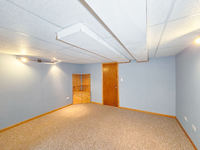 basement featuring a drop ceiling and carpet