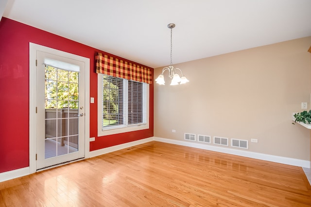 unfurnished dining area with wood-type flooring and a chandelier