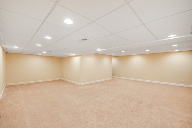 basement with light colored carpet and a paneled ceiling