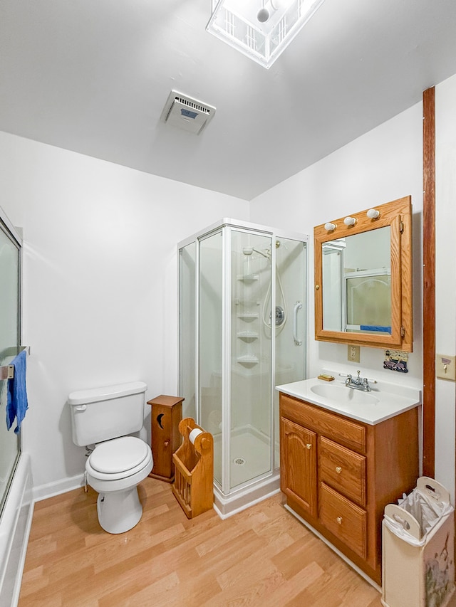 full bathroom with hardwood / wood-style floors, bath / shower combo with glass door, vanity, and toilet