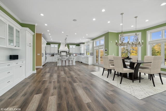 dining area with dark wood-type flooring, a chandelier, and crown molding