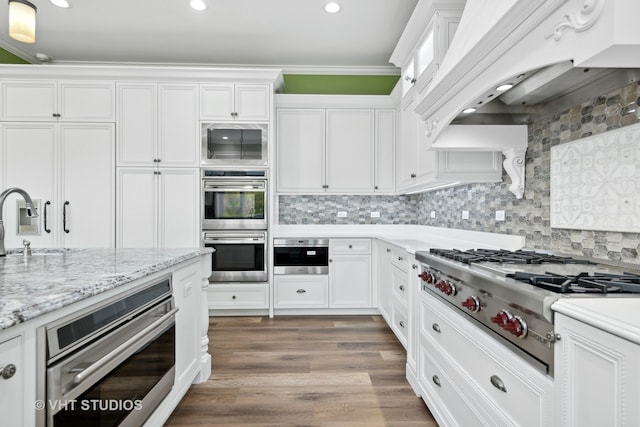 kitchen with premium range hood, crown molding, white cabinetry, appliances with stainless steel finishes, and dark hardwood / wood-style flooring