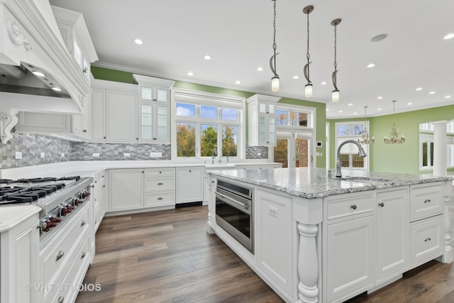 kitchen featuring white cabinets, custom range hood, a healthy amount of sunlight, and appliances with stainless steel finishes