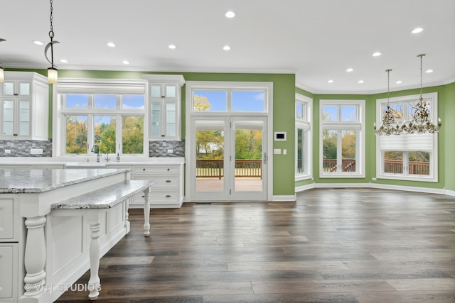 interior space with white cabinets, decorative light fixtures, dark hardwood / wood-style flooring, and tasteful backsplash